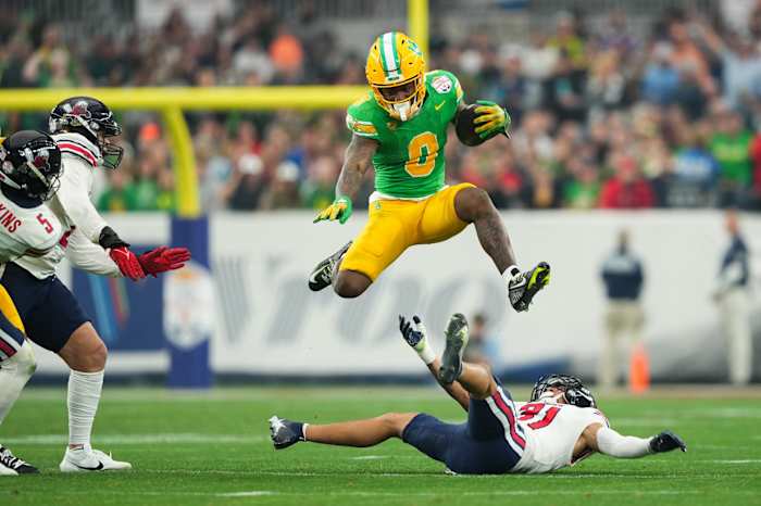 Jan 1, 2024; Glendale, AZ, USA; Oregon Ducks running back Bucky Irving (0) hurdles over Liberty Flames defensive back Brandon Bishop (6) during the second half in the 2024 Fiesta Bowl at State Farm Stadium. Mandatory Credit: Joe Camporeale-USA TODAY Sports  